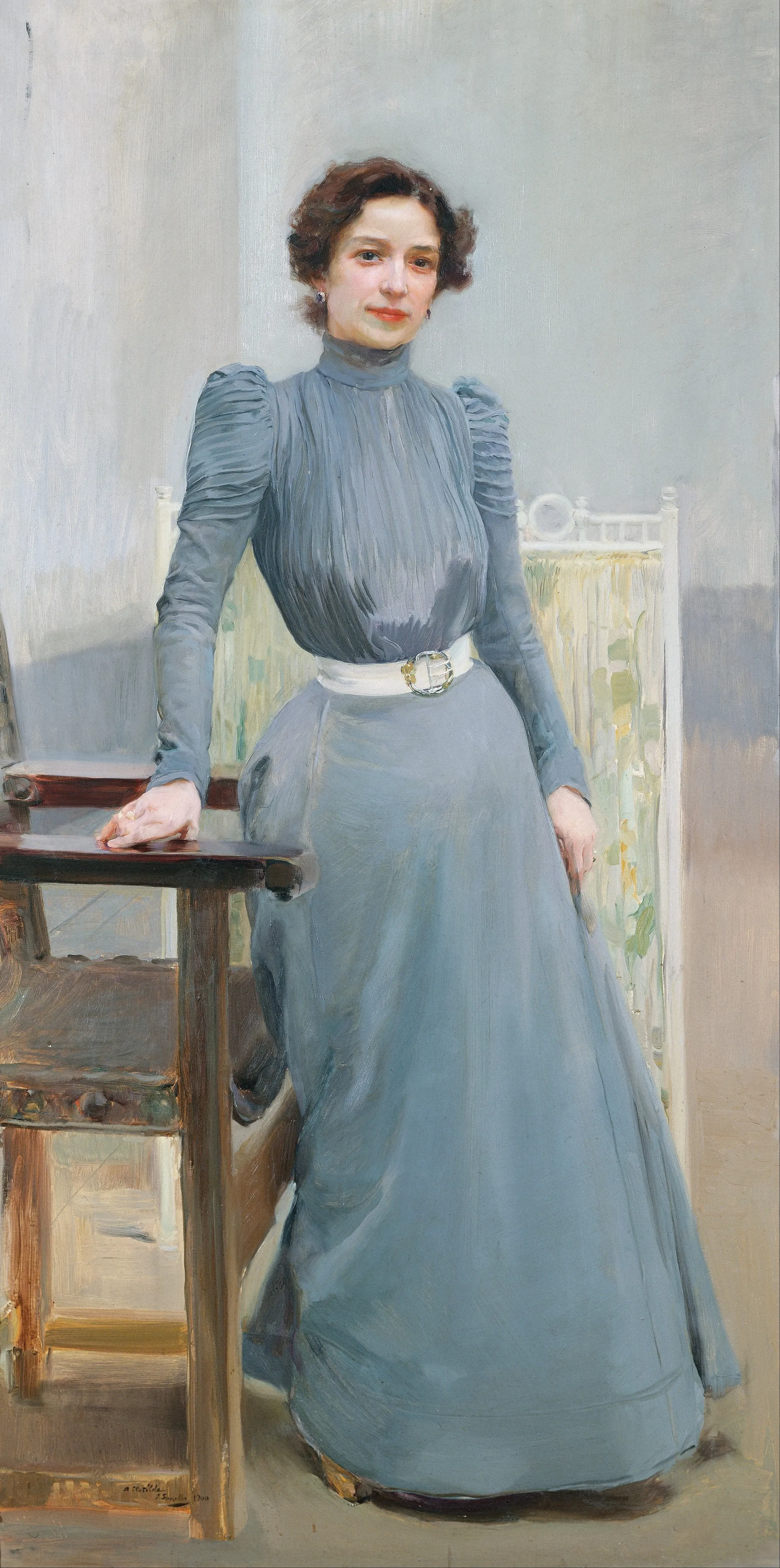 Sorolla's wife Clotilde stands full-length, poised and elegant in a shimmering grey gown against a dark, muted background.