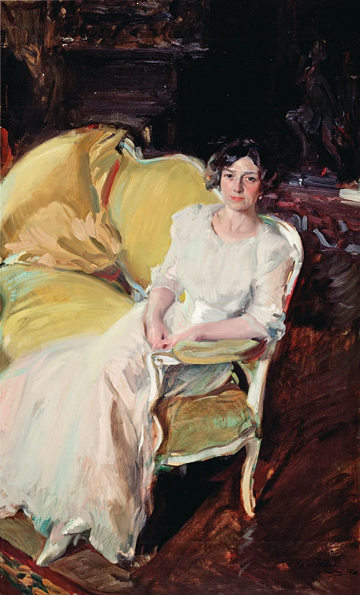 Sorolla's wife Clotilde sits poised on a sofa in an elegant gown, her relaxed pose and fabrics caught in soft interior light.