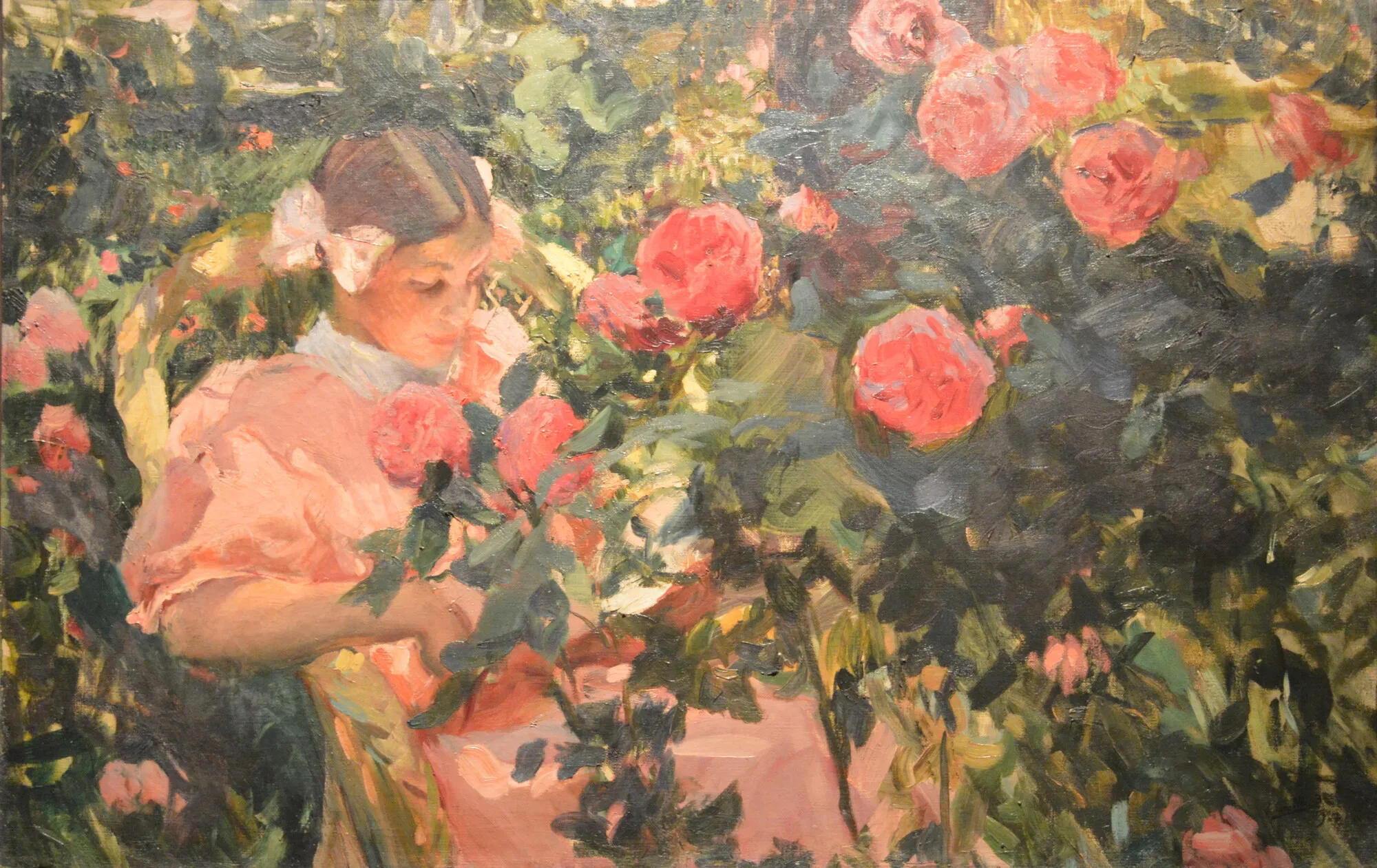 A young girl stands surrounded by blooming roses, sunlight and shadow playing across the flowers and her pale summer dress.