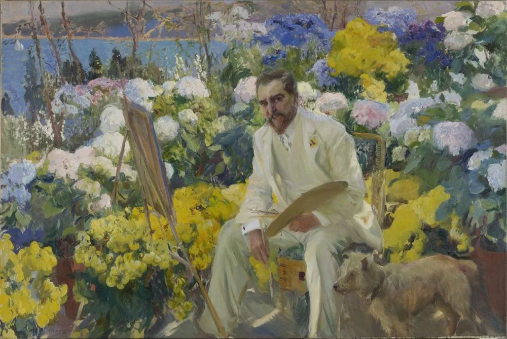 The artist Louis Comfort Tiffany sits in a white suit at his easel amid a blaze of garden flowers, painting in brilliant sunshine.