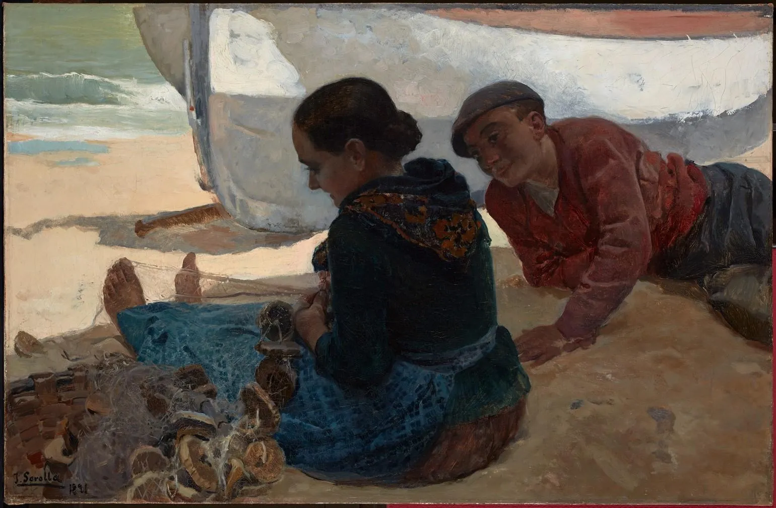 A boy in a red jacket lies on the sand grinning beside a woman mending nets against the hull of a beached fishing boat, the sea behind — an early beach scene in Sorolla's darker Valencian palette.